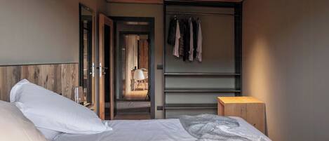 Ein Schlafzimmer mit einem Bett, einem Holzkopfstück, einem Kleiderschrank und einem kleinen Hocker.