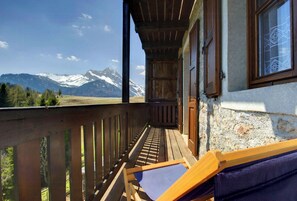 A balcony with a wooden railing, a wooden bench, and a balcony doors. - Historic dwelling with terrace in Sauris (Sauris di Sopra)