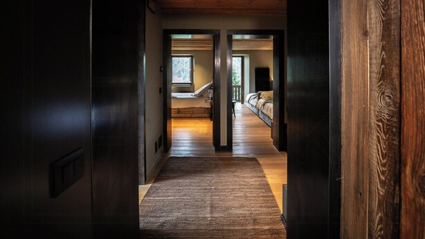 A hallway leading to a bedroom with a bed, a window, and a door. - Historic dwelling with terrace in Sauris (Sauris di Sopra)