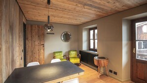 A room with a wooden ceiling, a round mirror, a table with chairs, and a window. - Historic dwelling with terrace in Sauris (Sauris di Sopra)