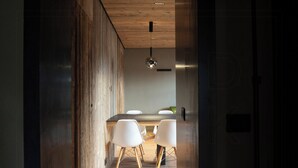 A modern kitchen with a wooden ceiling, a round hanging light, and a dining area with white chairs. - Historic dwelling with terrace in Sauris (Sauris di Sopra)