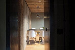 A modern kitchen with a wooden ceiling, a round hanging light, and a dining area with white chairs. - Historic dwelling with terrace in Sauris (Sauris di Sopra)