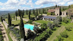 Une villa dotée d’une piscine, d’une architecture en pierre et offrant une vue sur la campagne.