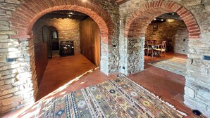 Un intérieur aux murs de pierre, agrémenté d’arches au niveau des portes, d’un tapis à motifs et d’une cheminée.
