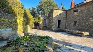Un bâtiment en pierre doté d’une cour, d’un petit étang orné de nénuphars et d’un espace extérieur aménagé pour s’asseoir.