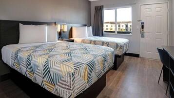 Een hotelkamer met twee bedden, een bureau en een raam met uitzicht.