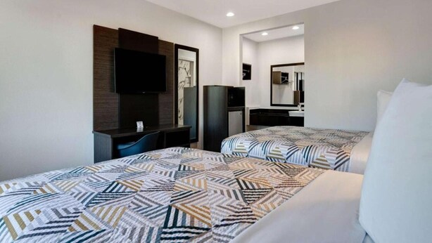 Una habitación de hotel con dos camas, televisión, escritorio y armario.