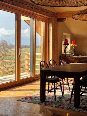Un comedor con una mesa y sillas de madera, un tapete colorido y vistas a través de grandes puertas correderas de cristal.