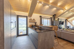 Eine moderne Küche mit einer großen Kochinsel, Holzbalken und Blick auf die Berge.