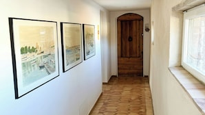 Ein Flur mit sechseckigem Bodenmuster, weißen Wänden und gerahmten Kunstwerken.