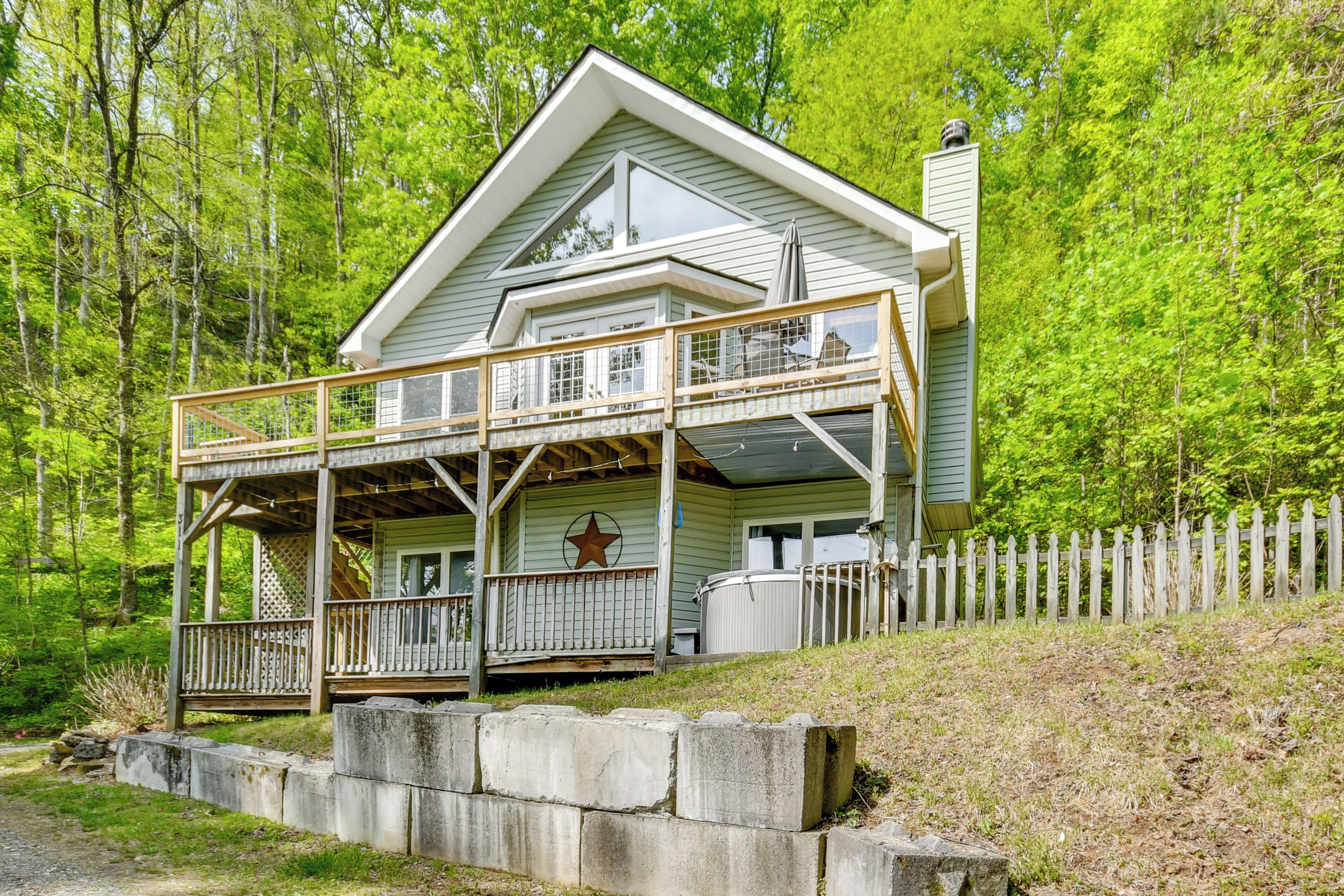 Une cabane à deux étages avec un balcon, une décoration en forme d’étoile et une clôture blanche en bois.