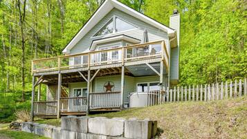 Une cabane à deux étages avec un balcon, une décoration en forme d’étoile et une clôture blanche en bois.