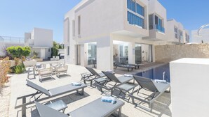 Un edificio moderno con piscina, area salotto esterna e cielo sereno.
