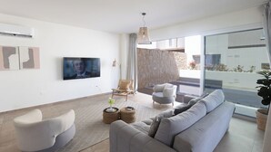 Un soggiorno moderno con un divano grigio, una TV a schermo piatto e una parete in pietra.
