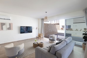 Ein modernes Wohnzimmer mit einem grauen Sofa, einem Flachbildfernseher und einer Steinwand.