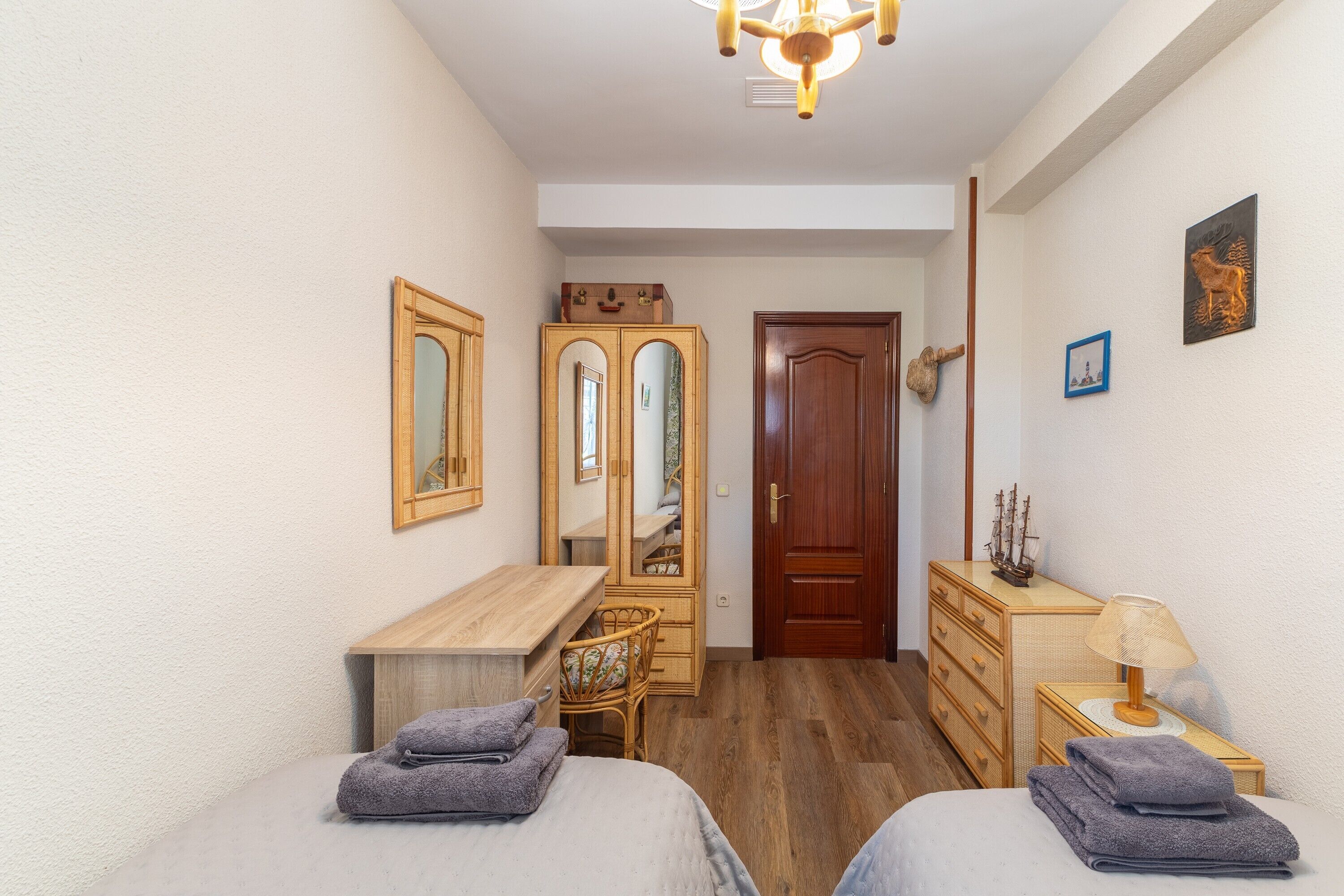 Un dormitorio con dos camas, un aparador de madera, un espejo y un escritorio de madera.