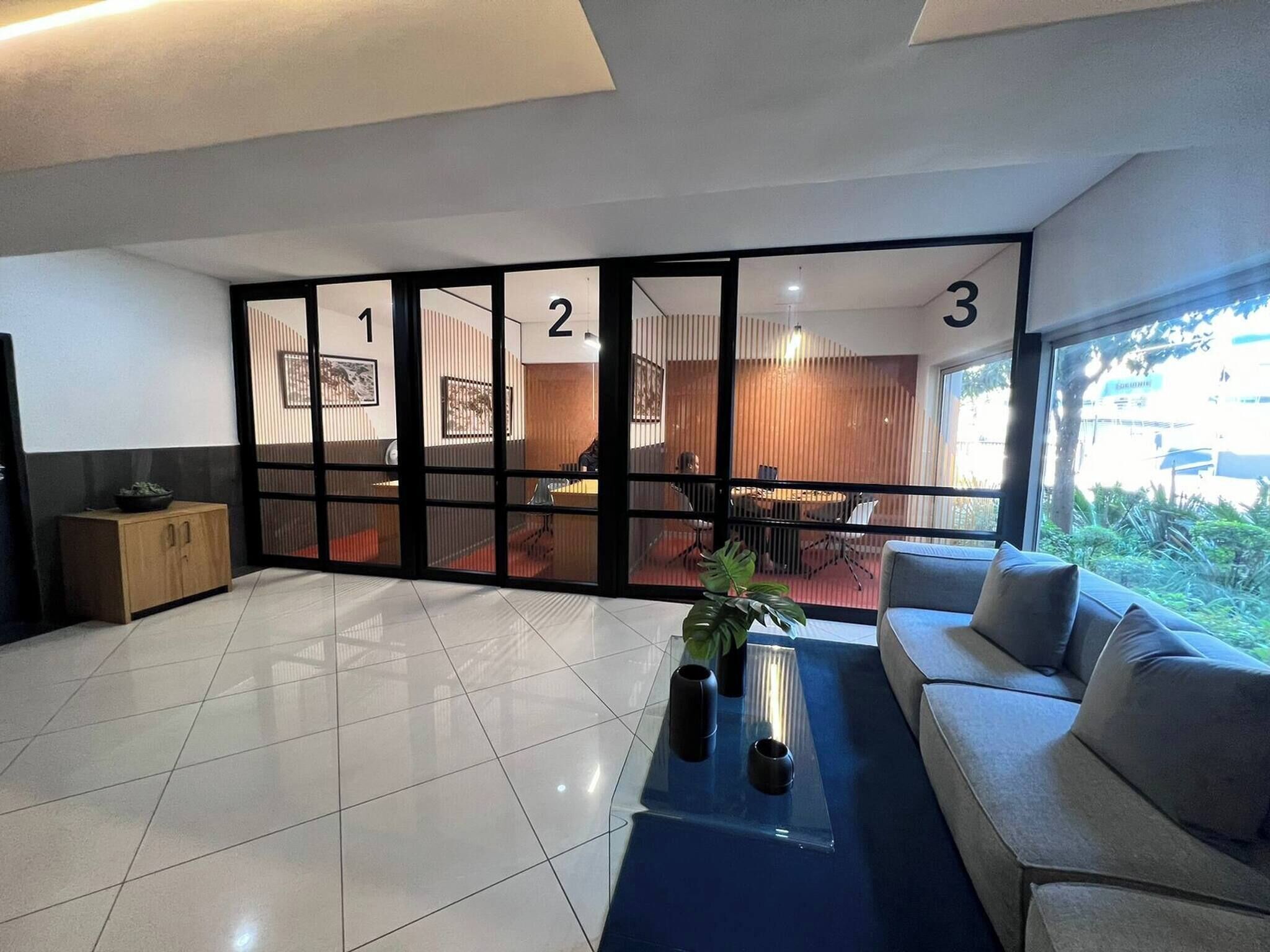 A modern interior with a tiled floor, a sofa, a coffee table, and a view through a glass door with numbered panels.