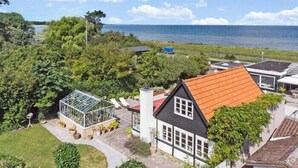 Una casa con techo rojo, un invernadero y vistas al mar.