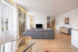 Ein modernes Wohnzimmer mit einer Couch, einem Fernseher und einer Treppe, die zu einer weiteren Ebene führt.