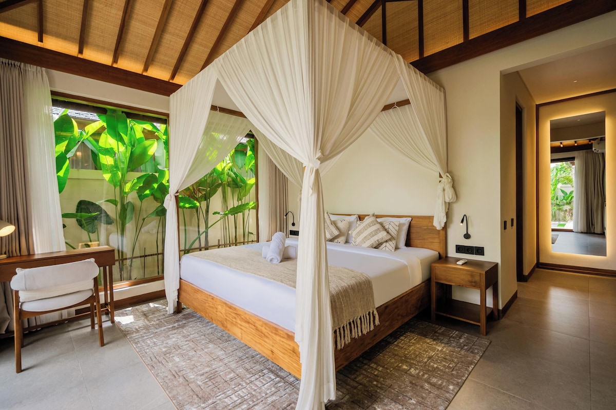 A bedroom with a canopy bed, a desk, and a chair.