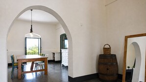 Ein Raum mit Holztisch und -stühlen, einer Hängelampe, einem Fass und einem Spiegel an der Wand.