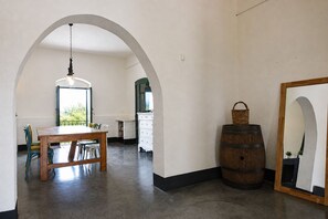 A room with a wooden table and chairs, a hanging light fixture, a barrel, and a mirror on the wall. - Villa Chiaramonte Gulfi (Chiaramonte Gulfi)