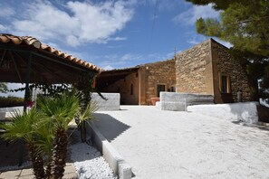 A stone building with a tiled roof, a covered patio area, and a white gravel ground. - Villa Chiaramonte Gulfi (Chiaramonte Gulfi)