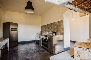 A kitchen with stainless steel appliances, a patterned backsplash, and a hanging light fixture. - Villa Chiaramonte Gulfi (Chiaramonte Gulfi)