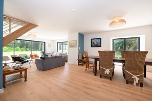 A spacious living area with a dining table and chairs, a sofa, and a staircase. - Holiday Home 'Riantec' with Private Terrace, Private Garden and Wi-Fi (Riantec)