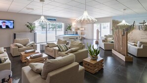 Een moderne hotellobby met banken, een pooltafel en uitzicht op het strand.