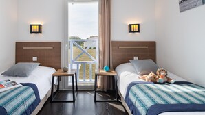 Une chambre d’hôtel avec deux lits, une petite table, une fenêtre donnant sur un paysage agréable et des lampes fixées au mur.