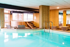 Ein Innenpool mit Holzwänden und einer Treppe, die zu einer erhöhten Ebene führt.