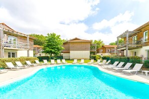 A swimming pool with lounge chairs, a wooden building, and a clear sky.