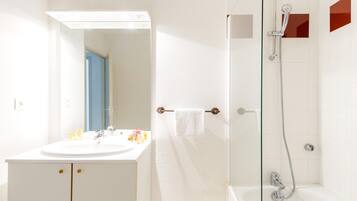 A bathroom with a white sink, mirror, and shower.