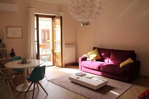 A living room with a round table, a sofa, a coffee table, and a large window with a view of buildings. - Cécile House - Palermo Historic Center (Palermo)