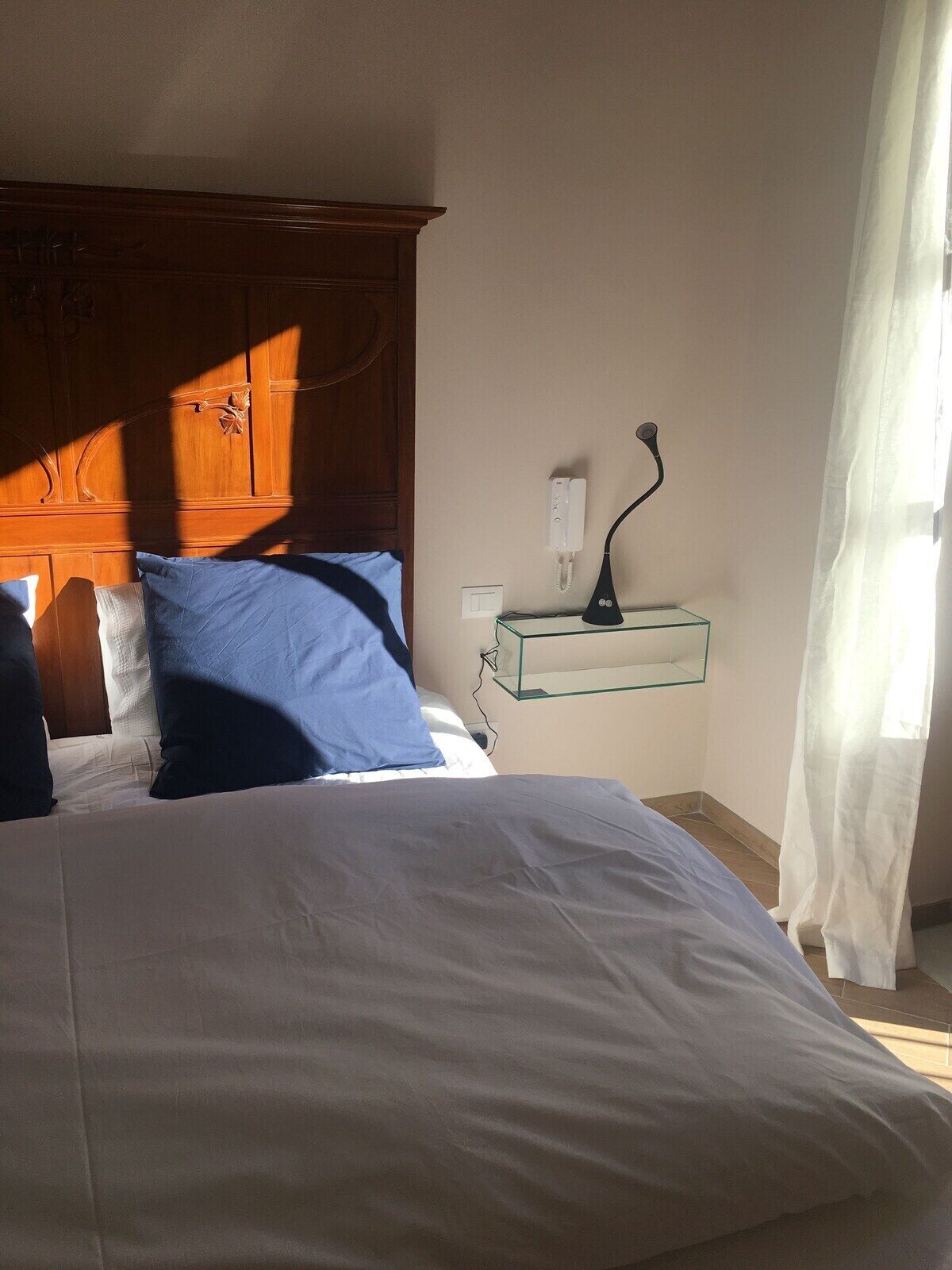 A bedroom with a bed, a nightstand, a lamp, and a telephone.