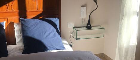A bedroom with a bed, a nightstand, a lamp, and a telephone.