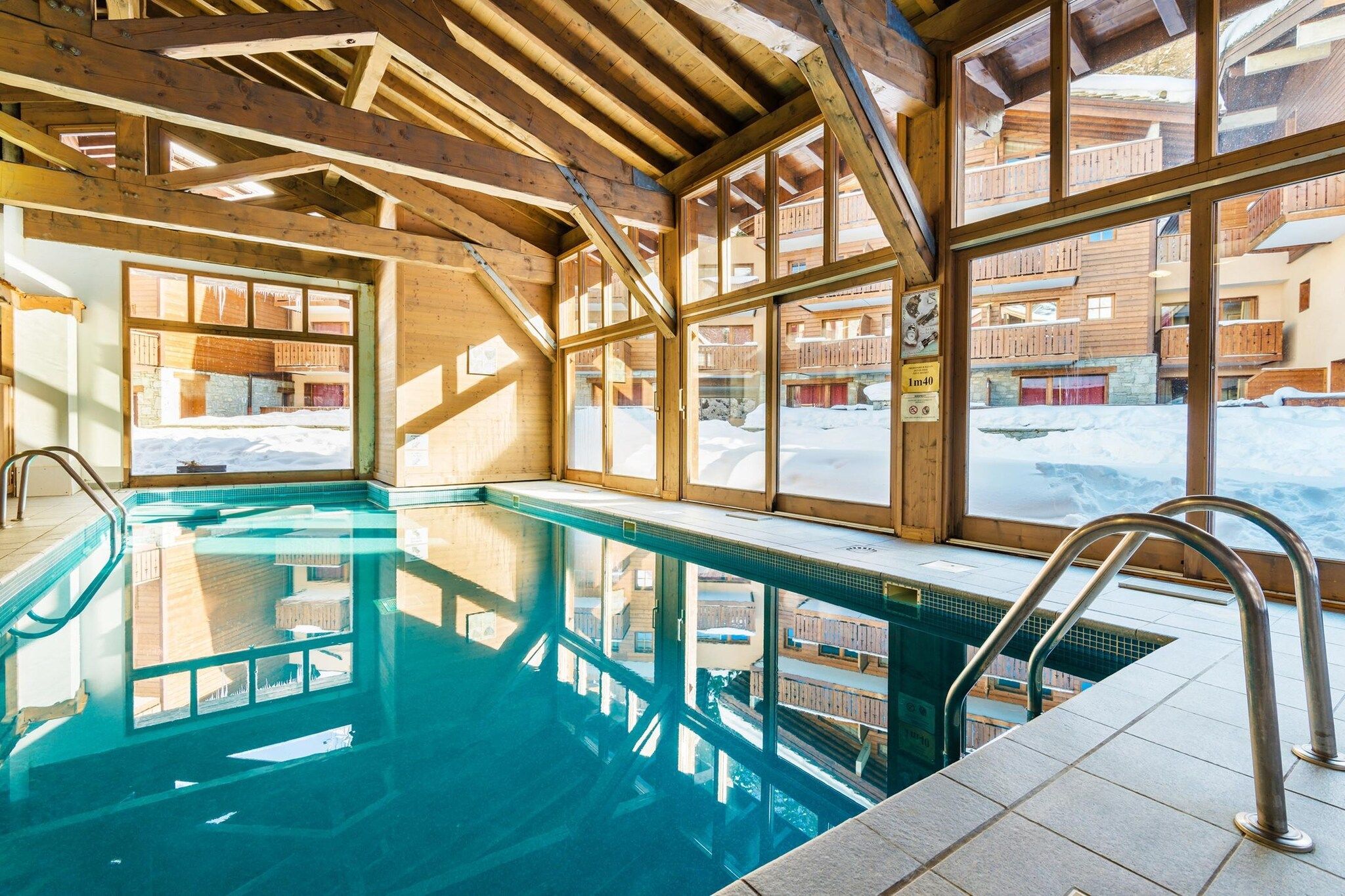 Une piscine intérieure avec des poutres en bois et de grandes fenêtres.