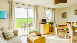 Ett vardagsrum med en soffa, ett soffbord, en TV och en matplats med stolar och ett bord.