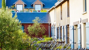 En bostadsbyggnad med ett blått tak, träbeklädda takkupor och en röd dörr.