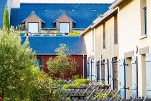 A residential building with a blue roof, wooden dormer windows, and a red door. - Coastal Apartment Escape in Cancale (Cancale)