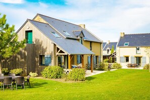 A residential building with a sloped roof, a wooden exterior, and a small garden area with outdoor furniture. - Coastal Apartment Escape in Cancale (Cancale)