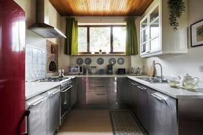 Una cucina moderna con elettrodomestici in acciaio inossidabile, forno integrato e una finestra con tende.