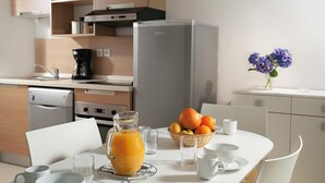 Eine moderne Küche mit Kühlschrank, Kaffeemaschine und Obstschale auf der Arbeitsfläche.