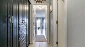 A hallway with a 'Beach' sign, a door, and a view into a room with a window. - Tides, Tennis & Tan Lines: Hilton Head Condo! (Hilton Head Island)