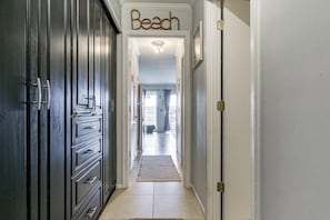 A hallway with a 'Beach' sign, a door, and a view into a room with a window. - Tides, Tennis & Tan Lines: Hilton Head Condo! (Hilton Head Island)