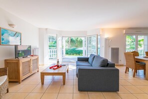 Ein modernes Wohnzimmer mit einer Couch, einem Couchtisch, einem Fernseher und einem Essbereich mit Stühlen und einem Tisch.