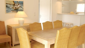 A dining area with a wooden table and wicker chairs, a white lamp, and a painting on the wall. - Villa for 6 People with Swimming Pool (Lacanau)