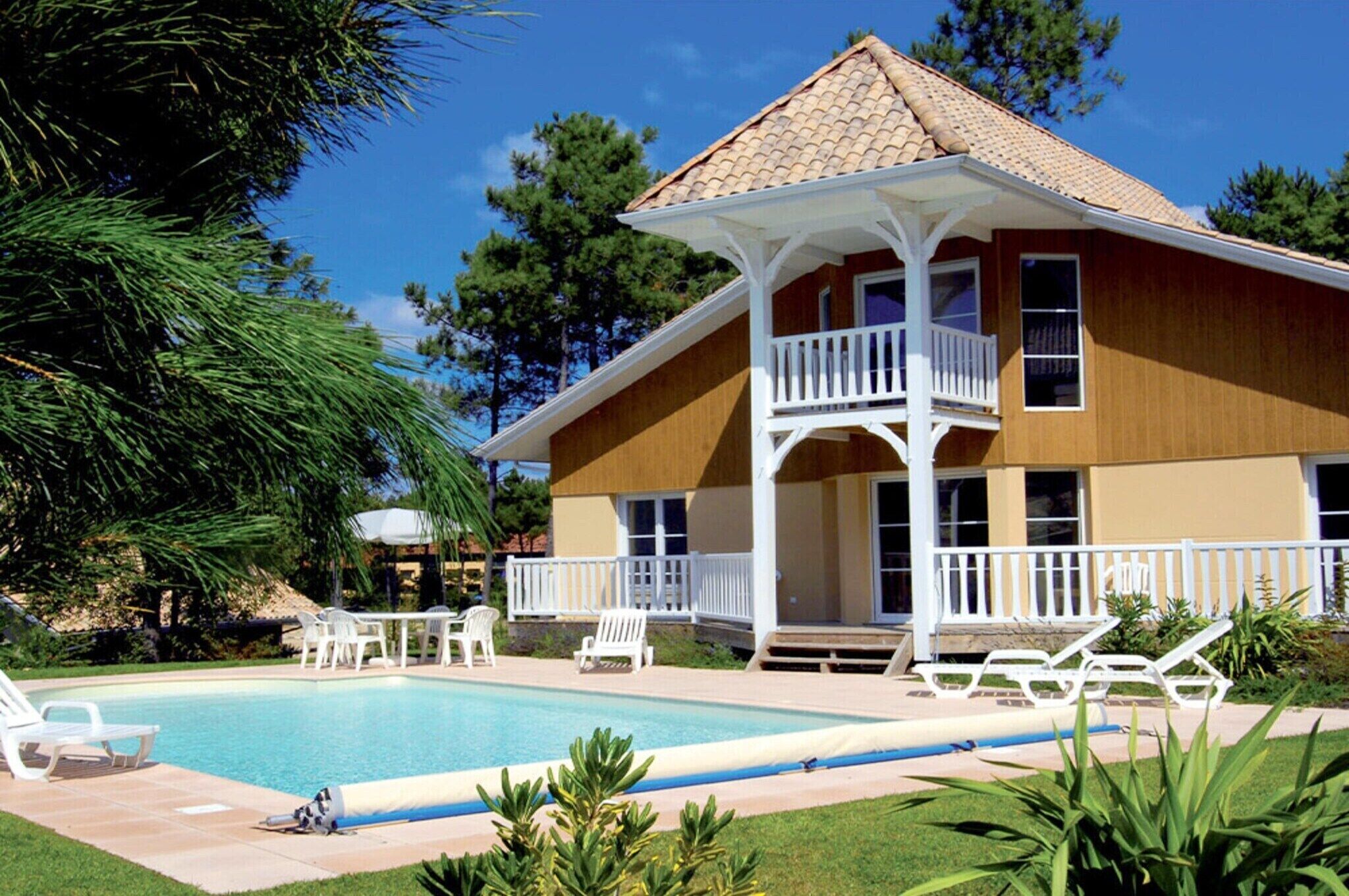 Une maison à deux étages avec une piscine, des balustrades blanches et une véranda couverte.