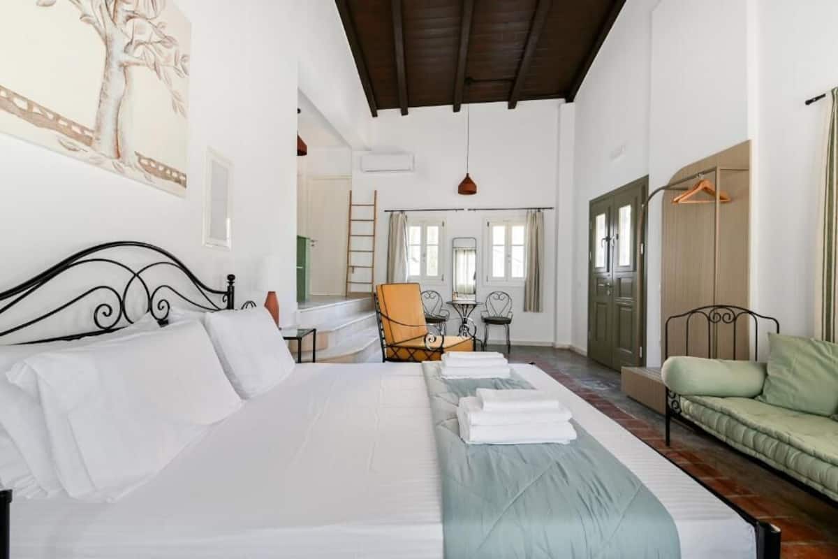 Un dormitorio amplio con una cama grande, un sofá verde, una silla y una mesa.